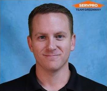 Young man smililng with brown hair wearing a black SERVPRO shirt