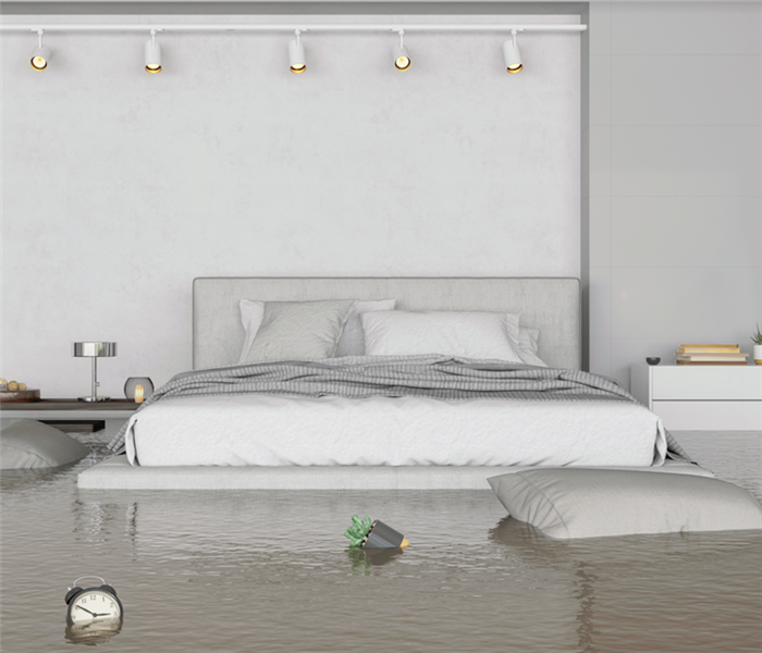 a flooded bedroom with water covering the floor and furniture floating around